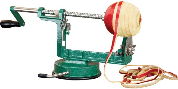 A green apple peeler with a suction base, peeling a red and yellow apple, with curled apple peels beside it.