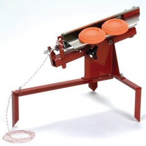 Red metal clay pigeon thrower with two orange clay targets and a pull cord.