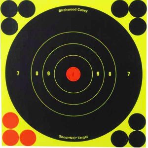 A Birchwood Casey Shoot-N-C target featuring a black circle with yellow borders and a central red bullseye. The target includes numbered rings and additional solid black circles for added aiming challenges.