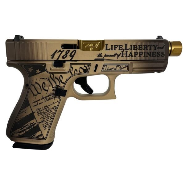 Tan-colored handgun with black engravings featuring "we the people," "1789," and "life, liberty and the pursuit of happiness," highlighted with a gold barrel end.