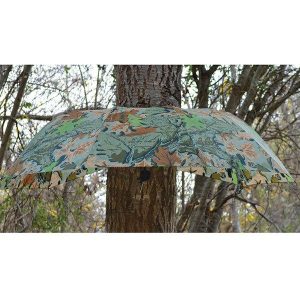 Camouflage-patterned umbrella with green and brown leaf design against a tree background.