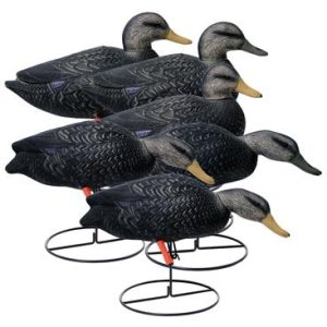A group of six black duck decoys with detailed feather patterns and yellow beaks, each mounted on a circular metal base.