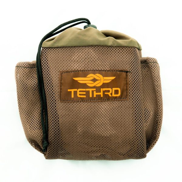 Brown mesh bag with "tethrd" logo in orange, featuring a black drawstring closure.