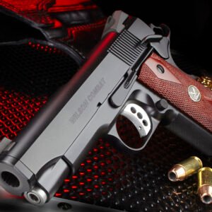 Silver and black handgun with textured brown grip, labeled "wilson combat," on a red and black patterned surface, surrounded by golden ammunition shells in casey, iowa.